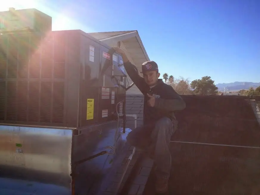 HVAC technician performing Air Duct Cleaning on a rooftop unit in West Livingston